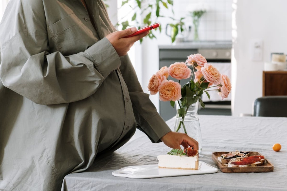 pregnant woman eating food and tracking weight gain on phone