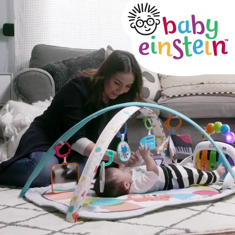 babies playing on a soft play mat and baby gym with sensory toys and piano